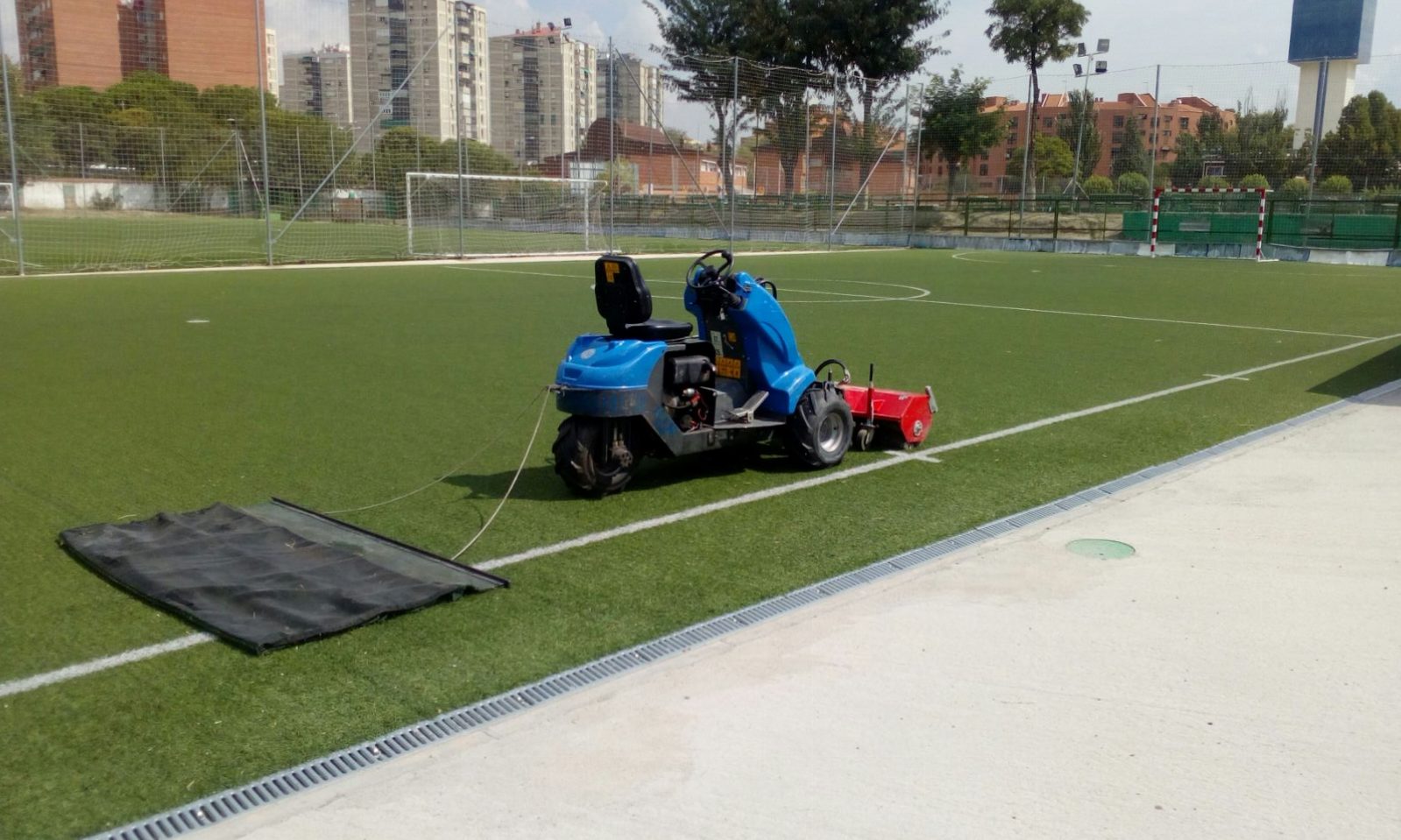 Tareas de mantenimiento especializado del césped artificial en un campo de fútbol.